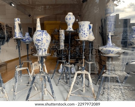 The ceramic objects of art in the gallery, ceramic in shop window, Art Museum, Architecture, Design exhibition. Handmade pottery, vases, semantic pieces in the window of the shop gallery, blue white