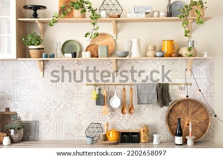 Ceramic plates, dishes, utensils and cozy decor on wooden shelfs. Kitchen wooden shelves with various ceramic jars and cookware. Open shelves in the kitchen. Stylish scandi cuisine interior decor. 