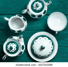 Ceramic service on colored wooden table. Ceramic teapot, cup, sugar bowl.