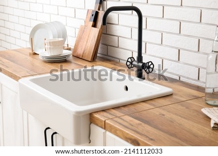 Ceramic sink on wooden counter near white brick wall