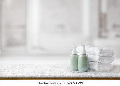 Ceramic Soap Green Bottles And White Cotton Towels On A Marble Counter Table Inside A Bright Bathroom Background.