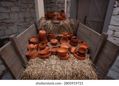 Ceramic tableware in an assortment on straw in a cart.
