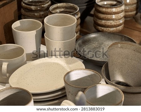 Ceramic tableware displayed on rustic surface under soft daylight, ideal for kitchen backgrounds. Mobile photo