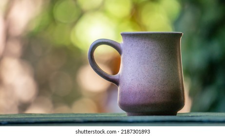 Ceramic tea cup on green wooden table. Blurry background with outdoor garden, plants and vegetation. Hot beverage mug and warm tones garden bokeh. - Shutterstock ID 2187301893