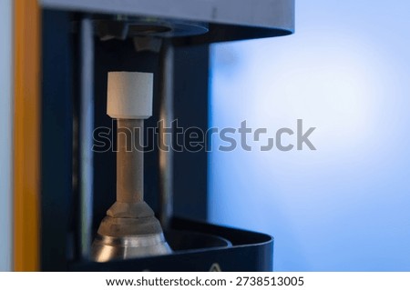 Ceramic test rod positioned in compression testing machine.