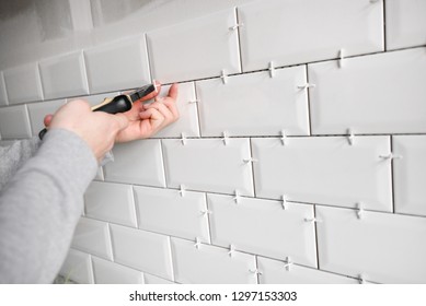 Ceramic Tile Lying. Installing New Subway Or Metro Tile In Bathroom, Shower Or Kitchen Back Splash During Home Renovation. Placing Or Taking Out Tile Spacers With Hands And Pliers.
