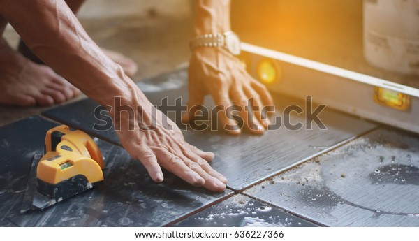 ceramic\
tiles. the worker\'s hand tile in position over adhesive with lash\
tile leveling system.selective focus.vintage\
tone