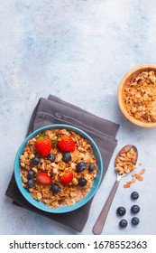 Cereal With Blue Berries And Slices Of Strawberries On A Blue Napkin, With A Spoon At The Side And A Small Bowl Of Cereal