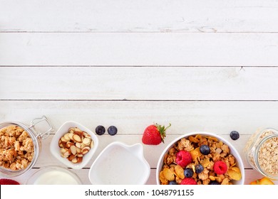 Cereal and ingredients for a healthy breakfast forming a bottom border over a white wood background. Top view. Copy space.