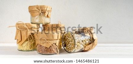 Cereals in glass jars on a light background with a shadow. Eco storage, zero waste.Long banner