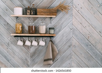 Cereals in glass jars on shelf, white cups, towel hang on hooks on kitchen  wooden wall. Cookware concept, kitchenware - Powered by Shutterstock