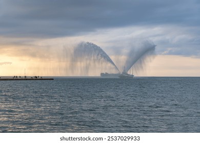 Ceremonial water salute by the tugboat in the sea port of Trieste. Sunset in Trieste, Italy. - Powered by Shutterstock