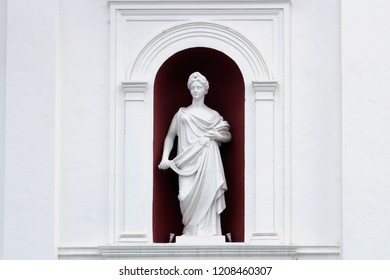 Ceres - The Goddess Of Agriculture. Classical Sculpture Of A Girl With A Sickle And Ears In A Niche Wall. Sculpture Of White Plaster.