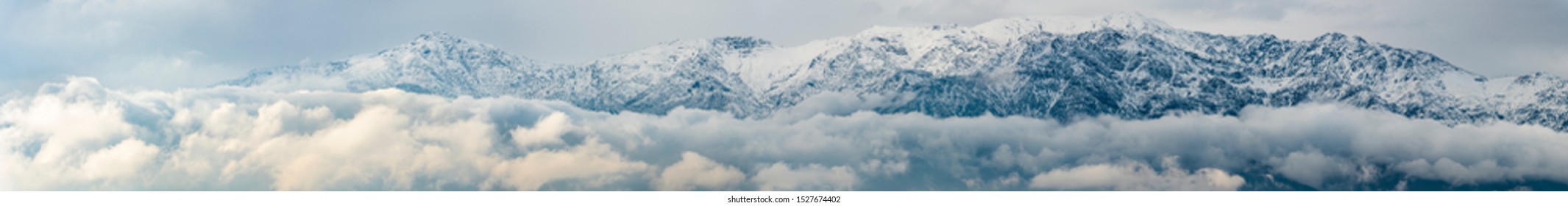 Cerro Ramon and Cerro La Cruz summits during a winter day. Snowcapped summits at central Andes mountains and amazing snowy rugged landscape on a cloudy day, an awe outdoor winter background scenery