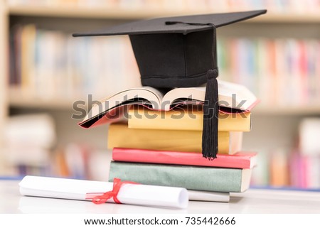 A Certificate and a Hat on Stack of Book against Blur bookshelf in University Library. Education Successful Program Concept. Setup studio shooting.