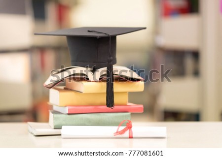A Certificate and a Hat on Stack of Book against Blur bookshelf in University Library. Education Successful Program Concept.Setup studio shooting.