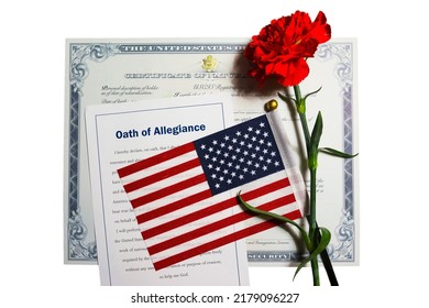 Certificate Of Naturalization, Oath Of Allegiance, American Flag And Red Carnation Flower Isolated On White Background Given To A New US Citizen After Naturalization Ceremony