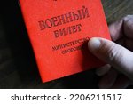 Certificate of Russian serviceman in hand, top view. Concept of mobilization in Russia, war in Ukraine, soldier, duty, reserve and army. Translation: Military ID card, Ministry of Defense.