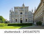 Certosa di Pavia monastery, historical monumental complex that includes a monastery and a sanctuary. green court and a church.The Ducale Palace on the right,Pavia,Italy.