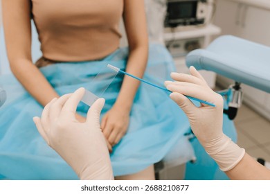 Cervical cells are applied to a microscope slide for examination. A Pap smear sample on a slide for testing. Gynecologist prepares a cytology slide using a sterile brush