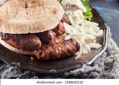 Cevapcici or cevapi served with lepinja bread and onion. Popular dish all over the Balkans