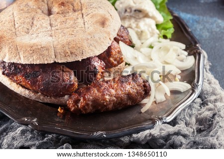 Cevapcici or cevapi served with lepinja bread and onion. Popular dish all over the Balkans