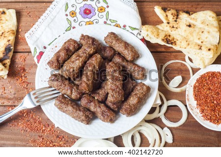 Cevapi, cevapcici, Balkan minced meat kebab served with onion, paprika flakes and Somun bread, Lepinja bread, over wooden background.
