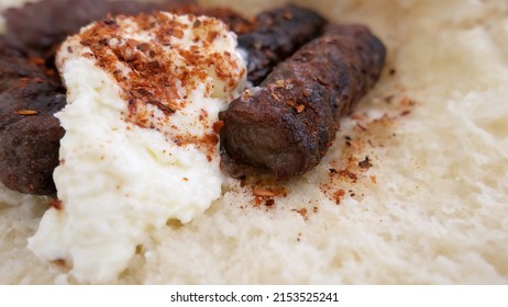 Cevapi - a traditional minced meat dish from the grill, served on a bun with creamy kaymak and paprika powder. Close up, macro