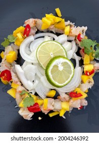 Ceviche From Fresh Shrimps With Mango, Onion And Lime Slices On A Black Plate Directly Above View