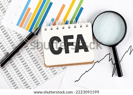 CFA text on notebook on graph background with pen and magnifier