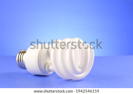 A CFL Compact Fluorescent Lightbulb over a soft blue background.