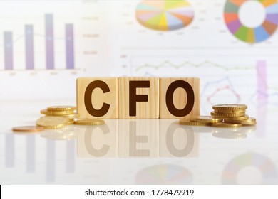 CFO the word on wooden cubes, cubes stand on a reflective surface, in the background is a business diagram. Business and finance concept