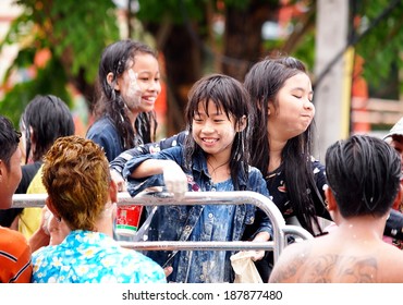 Chachoengsao Province 13 April 2014: Thai people and children wearing colorful clothes celebrate Songkran festival splashing water with bowls and water spray guns on the street in cities of Thailand
