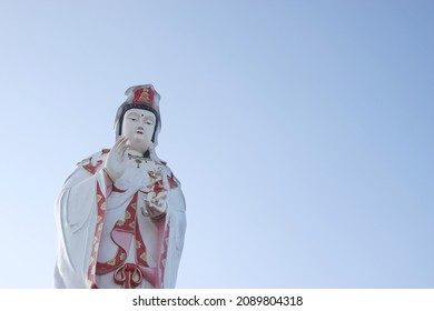 CHACHOENGSAO, THAILAND – DECEMBER 12, 2021: A statue of the Lady Buddha or Guan Im standing with a baby on hand for sky background on evening at Wat Saman Rattanaram temple in Chachoengsao province.