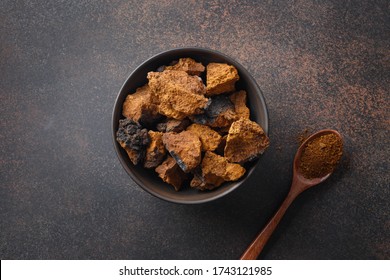 Chaga birch edible mushrooms in bowl on natural dark brown table. View from above. Close up.
