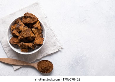 Chaga mushrooms in bowl on light table. Trendy healthy superfood for infusion, tea or coffee. Copy space. Top view.