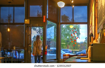 Chagrin Falls, Ohio / USA - November 18, 2018: Woman Walking Out Front Door Of Chagrin Falls Starbucks Coffee Shop On A Cold Autumn Day