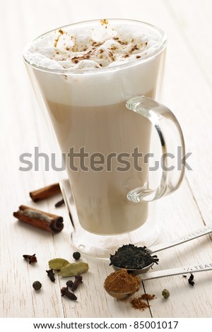 Chai latte spiced tea beverage in glass mug with spices