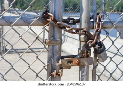 Chain link fence locked with heavy duty chain  and security to prevent a breach or unauthorized entry.