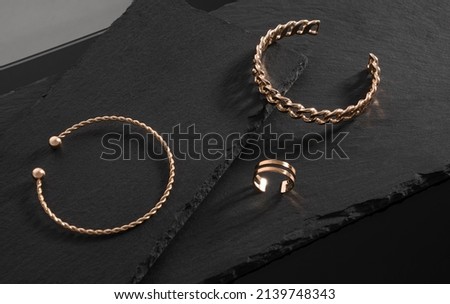 Chain and spiral shape bracelets and Gold ring on black stone trays with copy space
