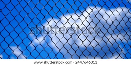 Chainlink fence detail with clouds and sky in background