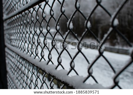A chain-link fence that is frozen and snowed in