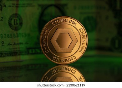 Chainlink LINK Cryptocurrency Physical Coin Placed on reflective surface with one dollar note behind and lit with green light