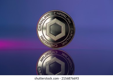 Chainlink LINK Cryptocurrency Physical Coin Placed on Reflective surface and lit with blue and purple lights. Macro Shot.