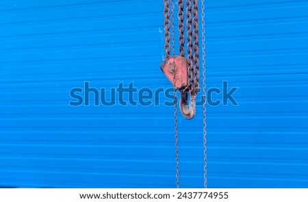  Chains and crane hook on a river dam.A crane on a dam against a blue curtain, an electric water turbine.