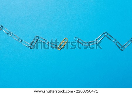 Chains formed by clips in which an orange link serves as a link. Mediator concept. Blue background.