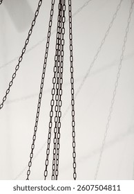Chains hanging from the ceiling casting shadows on a wall
