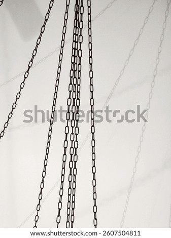 Chains hanging from the ceiling casting shadows on a wall