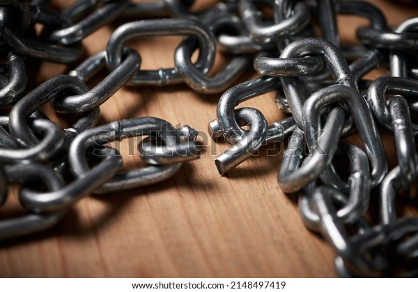 Chains are only as strong as their\
weakest links. Shot of metal chains with a broken\
link.