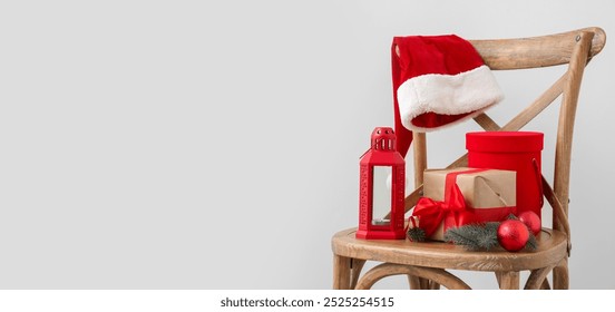 Chair with Christmas gifts, lantern and Santa hat on grey background with space for text - Powered by Shutterstock